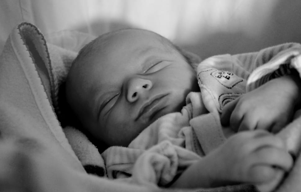 grayscale photography of baby sleeping in bassinet preview