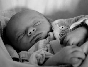 grayscale photography of baby sleeping in bassinet thumbnail