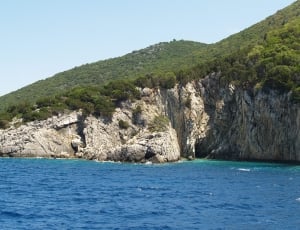 grey and green cliff of mountain near  blue ocean thumbnail