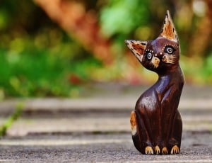 brown and maroon wooden cat decor on gray pavement thumbnail