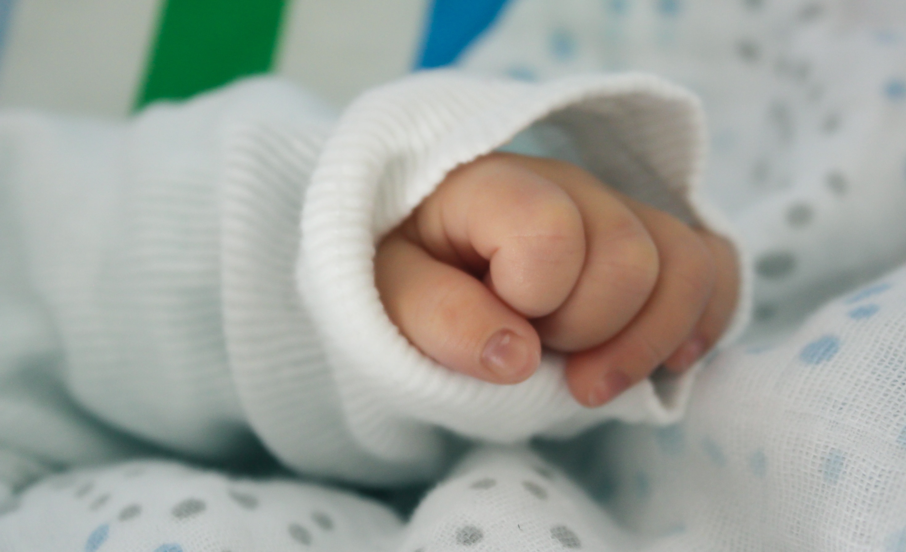baby in white jacket with selective blurry  photography of his hand