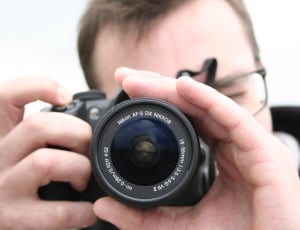 person holding black compact camera thumbnail