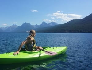 woman riding on green kayak near mountains during daytime thumbnail