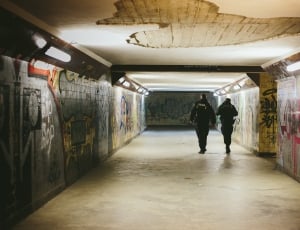 two man in black suit on grey and yellow wall with graffiti art thumbnail