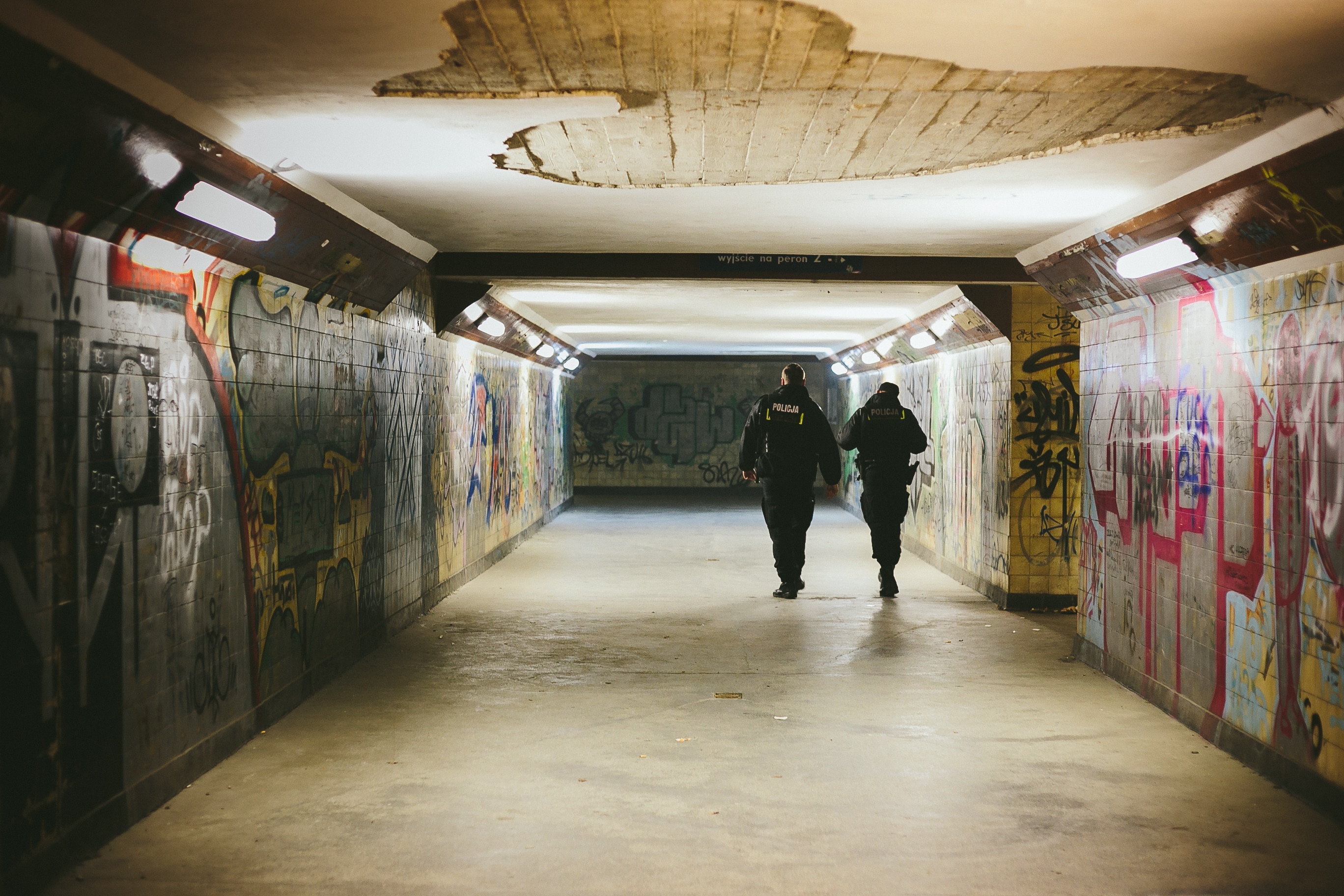 two man in black suit on grey and yellow wall with graffiti art