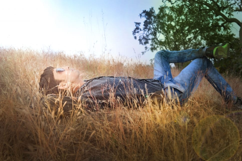 person in black shirt wearing blue jeans laying on green grass field preview