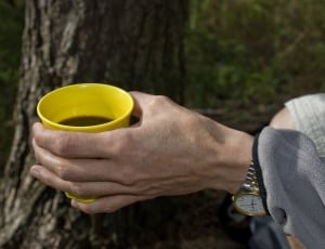 person in gray jacket holding yellow half-filled cup thumbnail