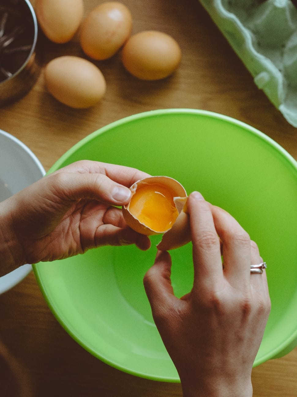 person holding cracked egg on top of bowl preview