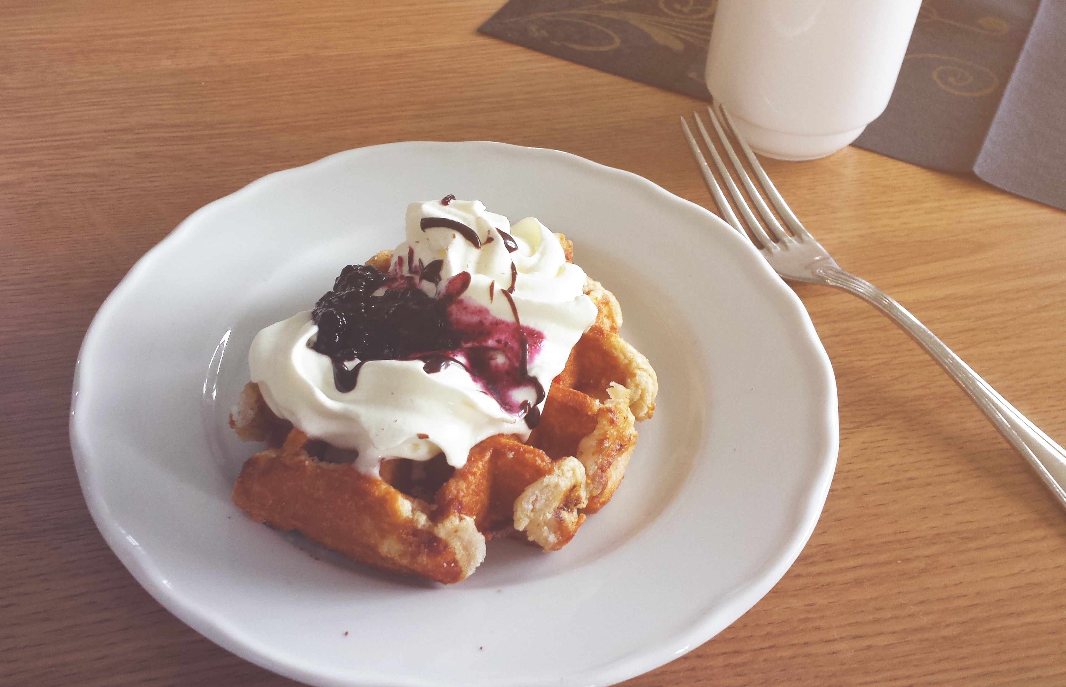 photo of waffle with cream and blue berry syrup