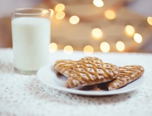 white ceramic plate with three heart shape cookies beside glass of milk thumbnail