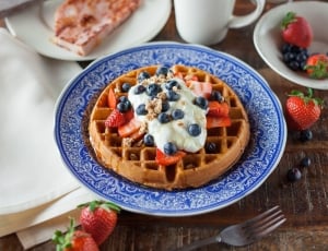Waffle Topped With Black Round Fruit and Strawberries thumbnail