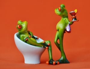 tree frog sitting on a white egg chair with another tree frog standing in front holding a martini glass thumbnail