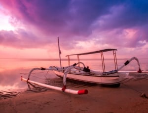 white sail boat on seashore during sunset thumbnail