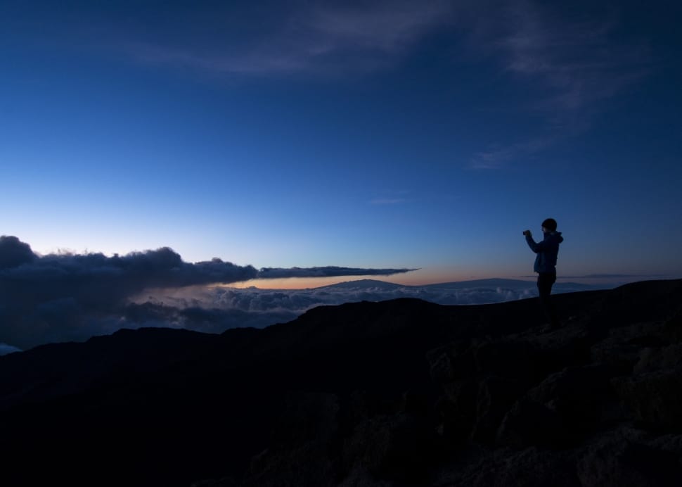 silhouette of person on muntains peak during night time preview