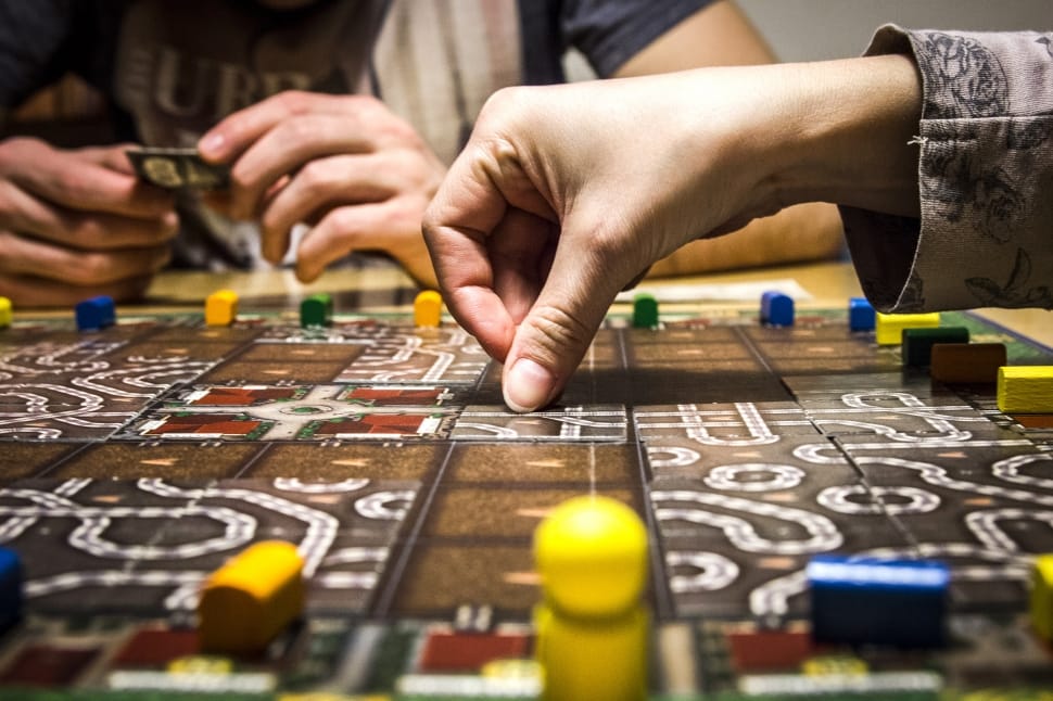 people playing a brown and white board game preview
