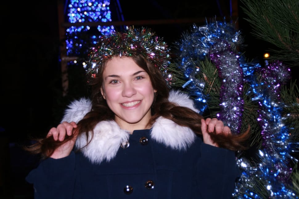 woman in blue and white furlined jacket with christmas decor on head while holding her hair preview
