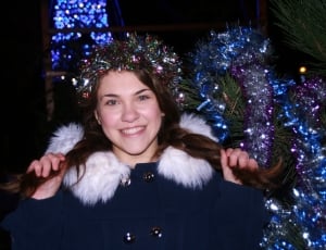woman in blue and white furlined jacket with christmas decor on head while holding her hair thumbnail
