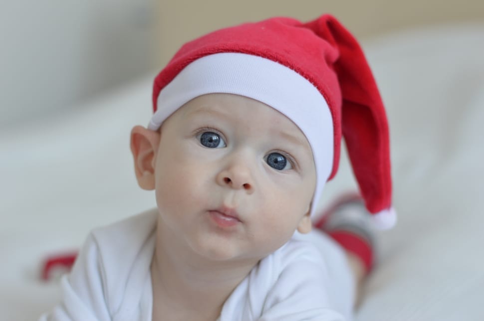 baby in red santa claus hat laying on bed preview