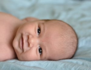 baby smiling while lying on bed thumbnail