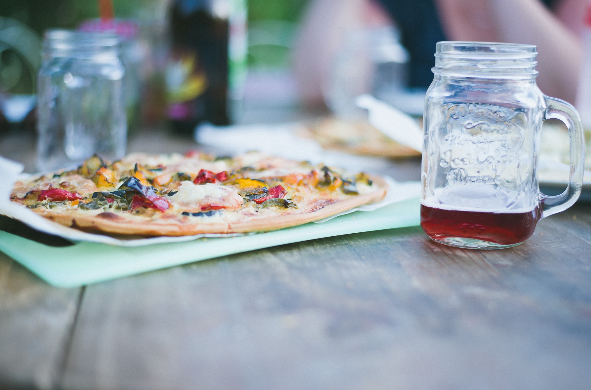 shallow focus photography of glass mug near round pizza on brown wooden table