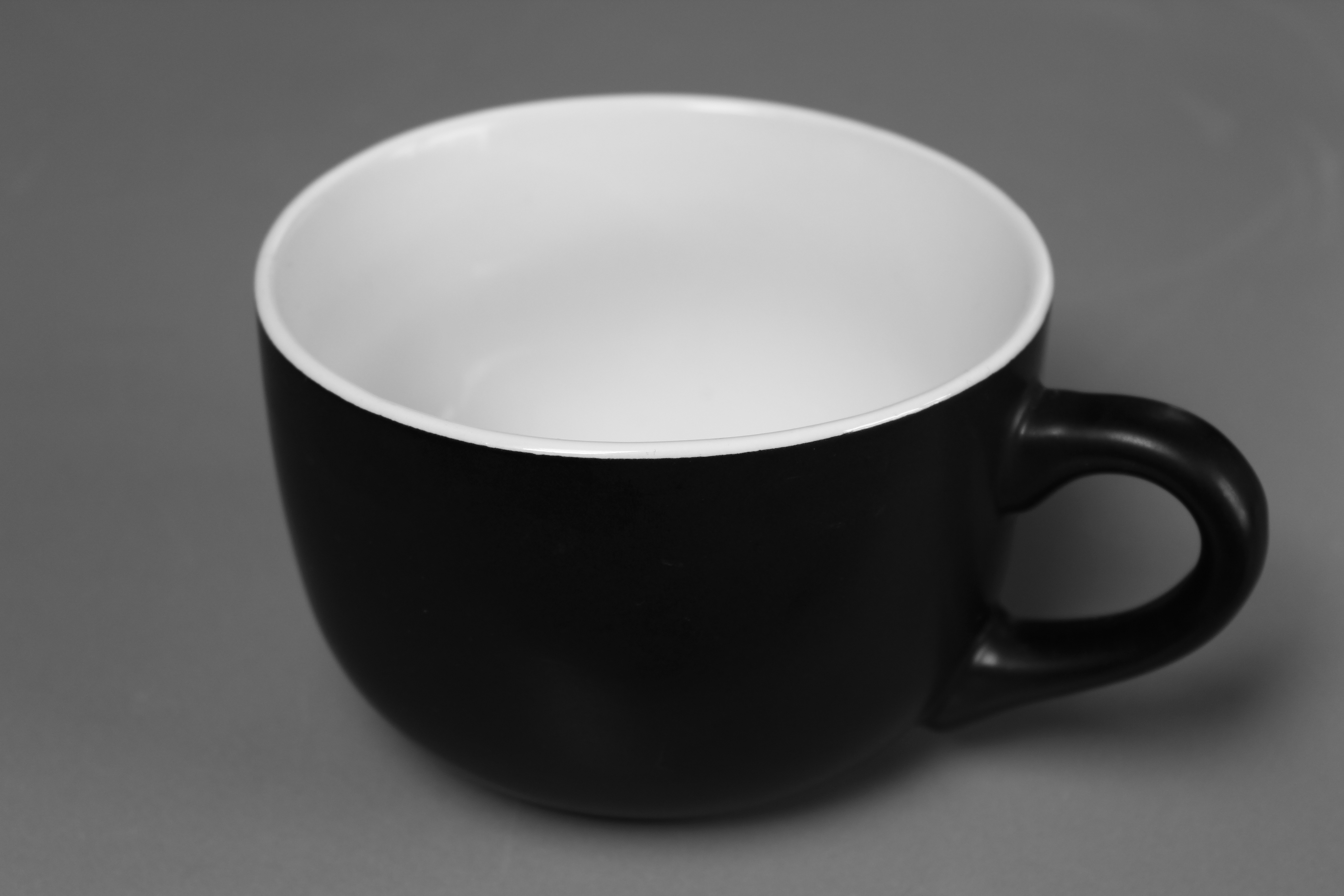 black and white ceramic coffee mug on gray textile