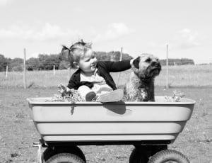 girl sitting on pull along wagon beside dog thumbnail