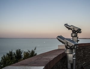 two gray telescope near body of water thumbnail