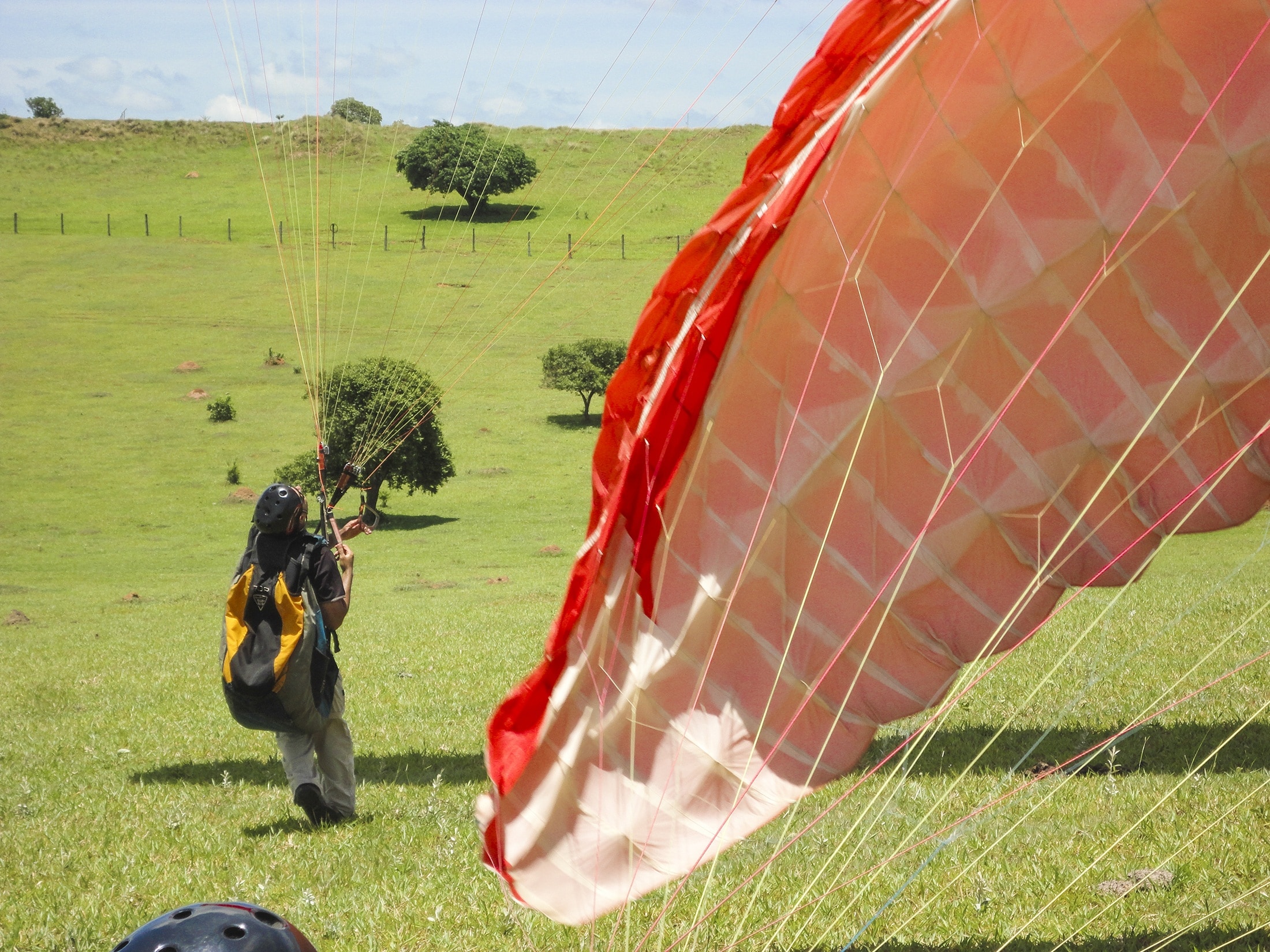 man landed with a parachute on green grass field