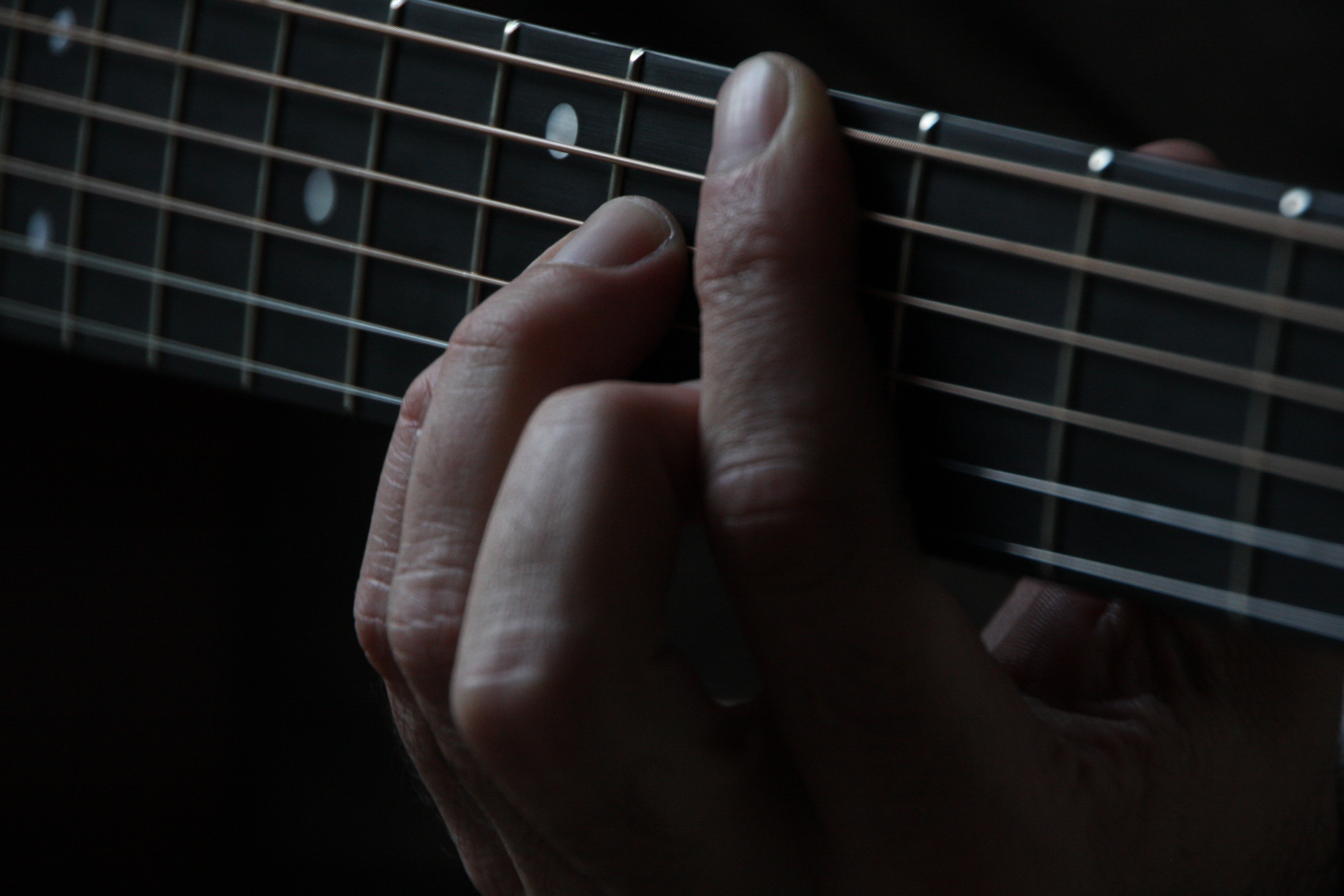 person playing guitar showing chord on fret board
