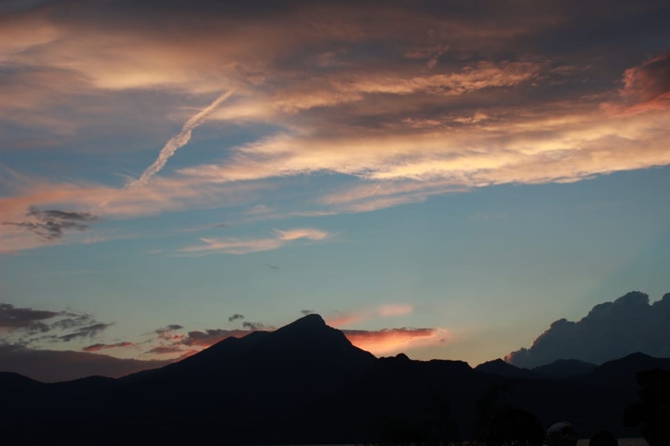 silhouette of mountain under cloudy sky during sunset preview