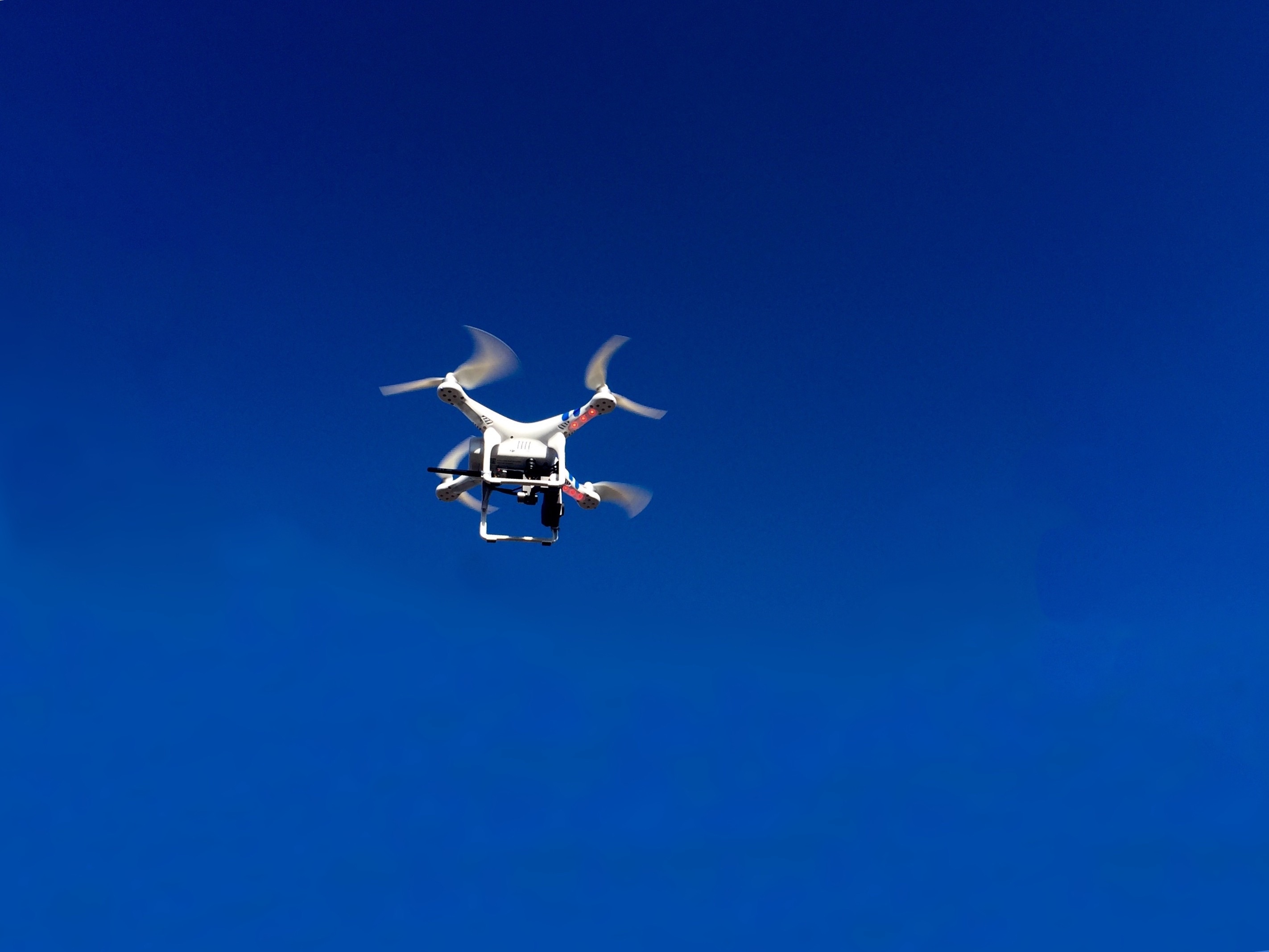flying white quadcopter  during daytime