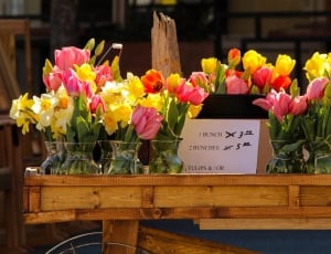 yellow and pink flowers on brown wooden cart thumbnail
