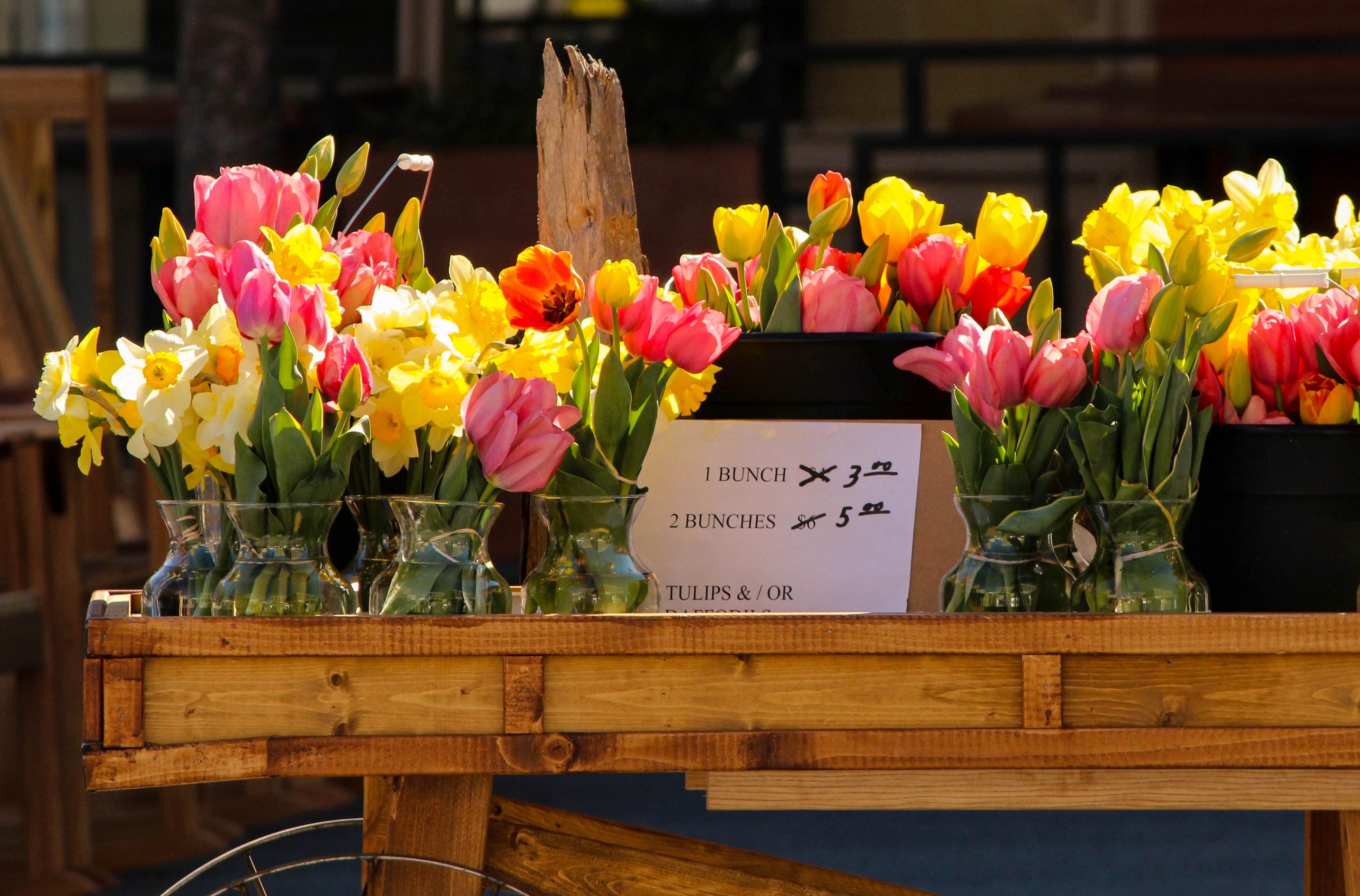 yellow and pink flowers on brown wooden cart