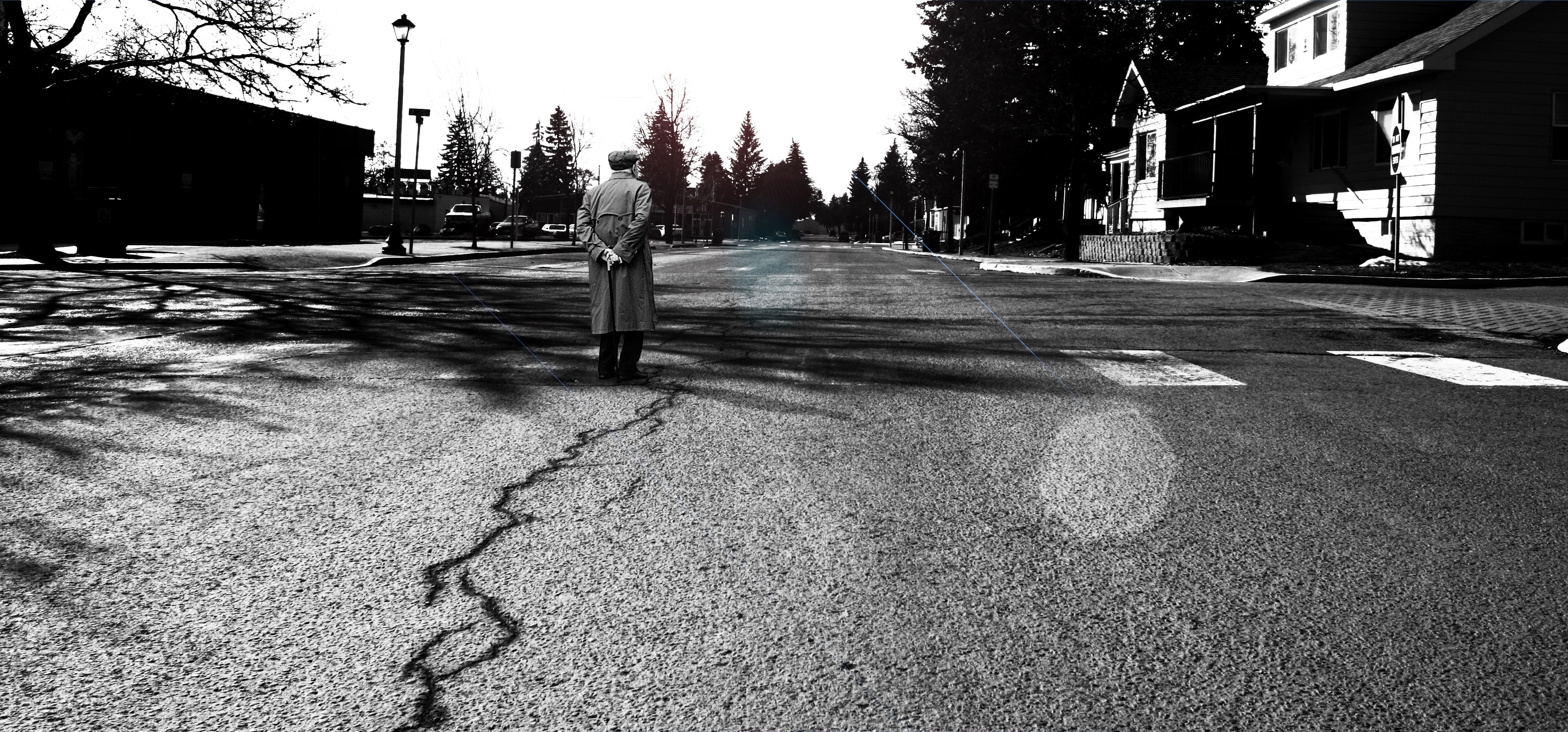 grayscale photo of man standing on gray concrete pavement