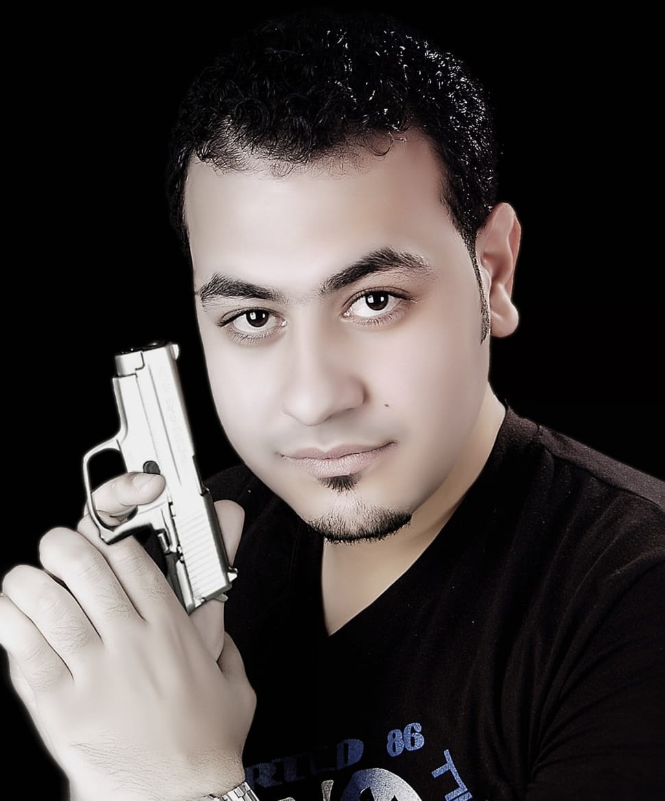 man in black v neck shirt holding gray semi automatic pistol preview