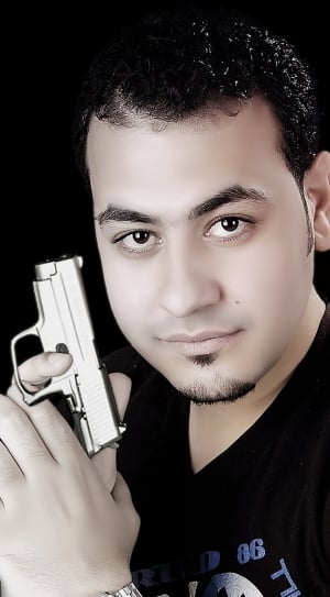 man in black v neck shirt holding gray semi automatic pistol thumbnail