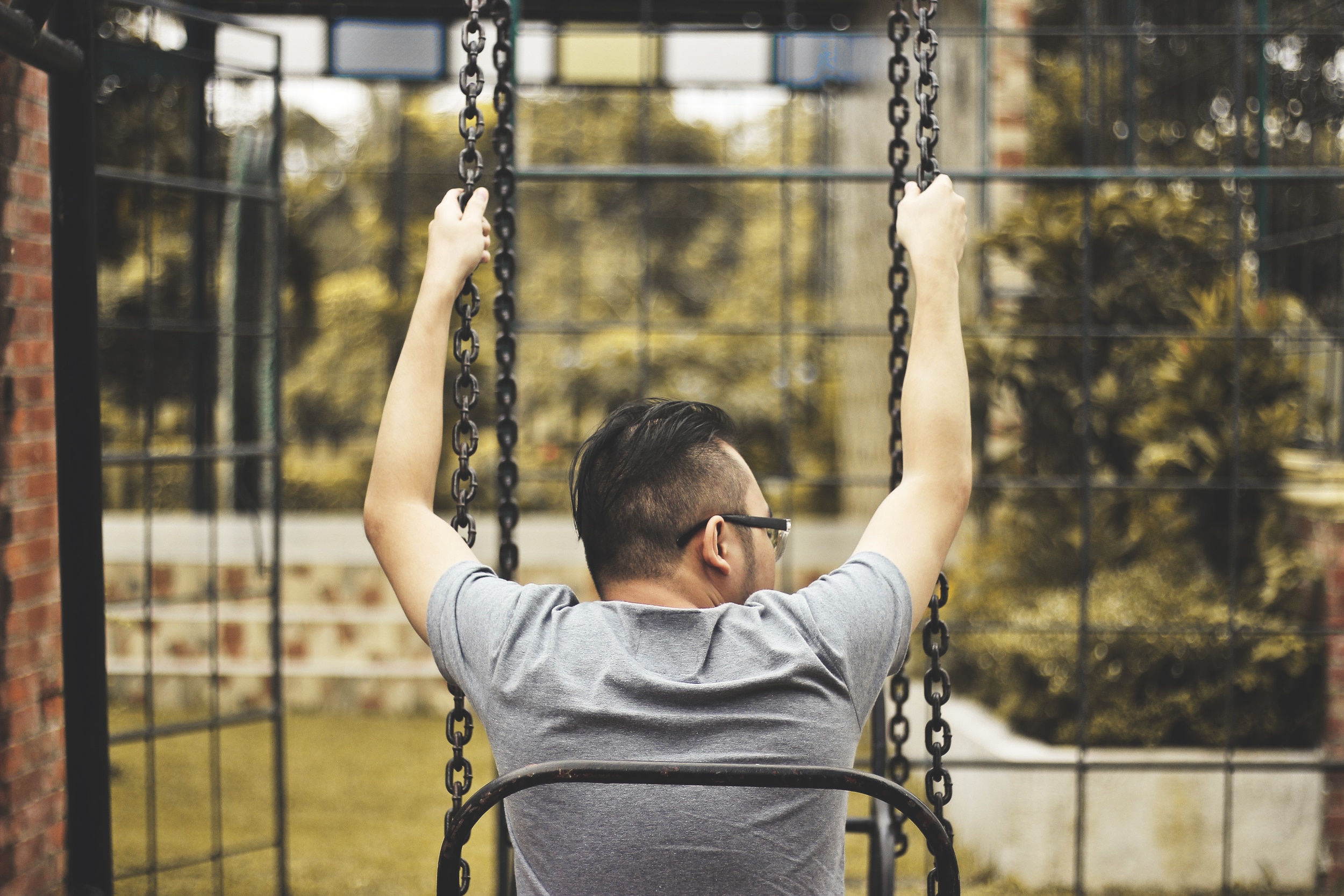 man sitting in swing during day time