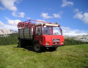 red industrial truck on green grass field at daytie thumbnail