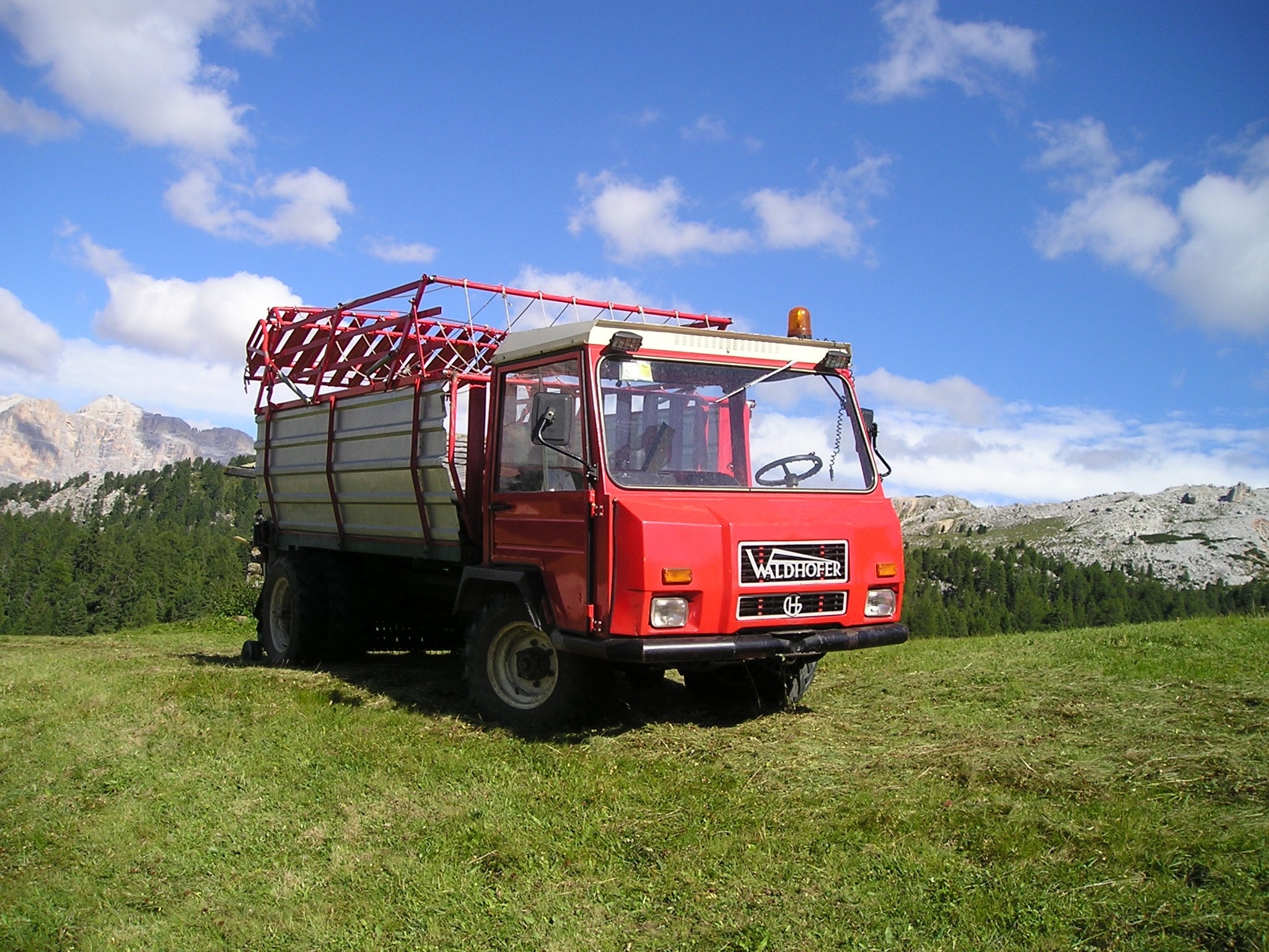 red industrial truck on green grass field at daytie
