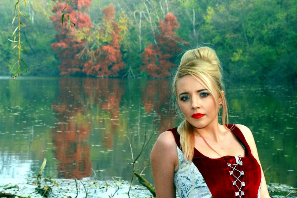 photo of lady wearing red and gray top near body of water preview