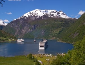 passenger boat on body of water between green and glacier mountains thumbnail