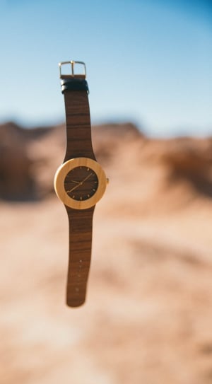 shallow focus photography of round brown and yellow analog watch with brown strap thumbnail