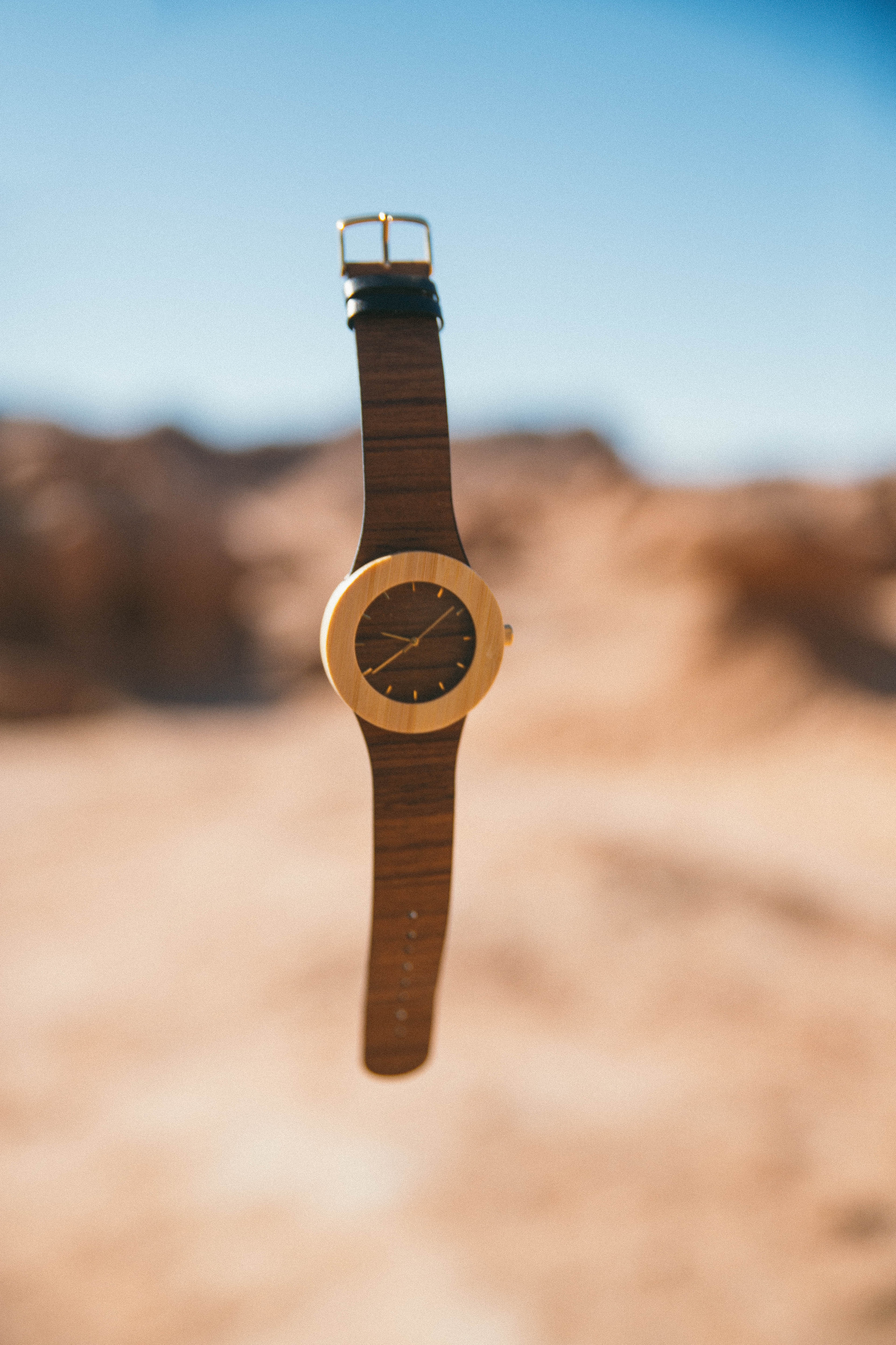 shallow focus photography of round brown and yellow analog watch with brown strap