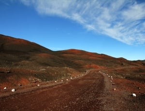 brown road beside green mountain during daytime thumbnail