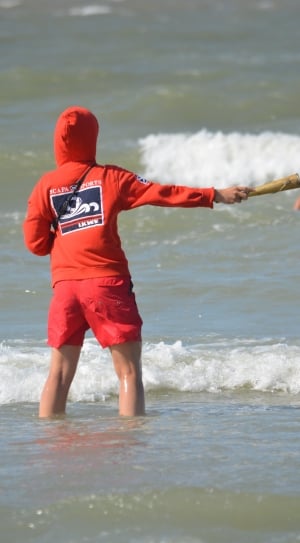 person wearing orange zip-up hoodie and red shorts in the ocean thumbnail