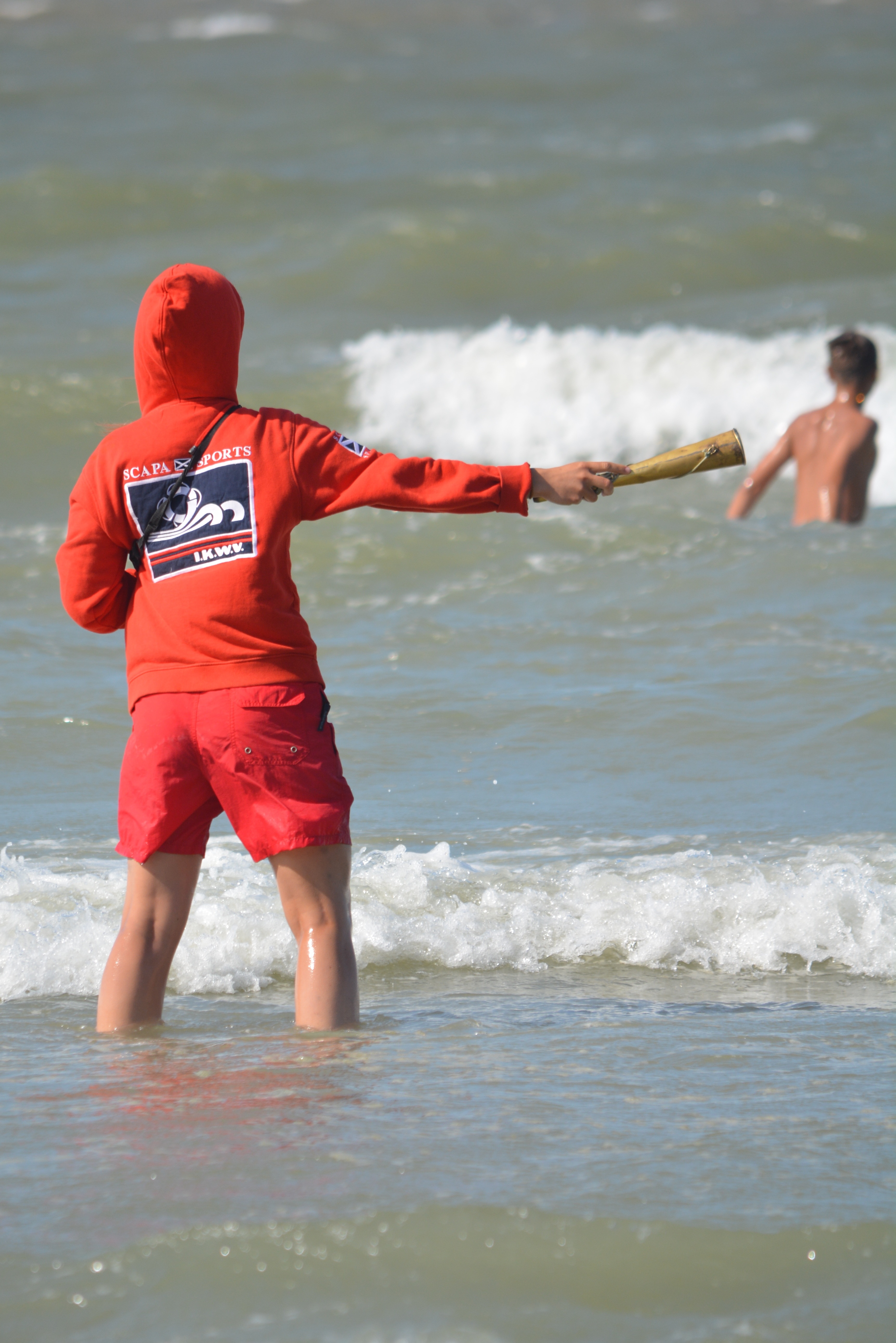 person wearing orange zip-up hoodie and red shorts in the ocean