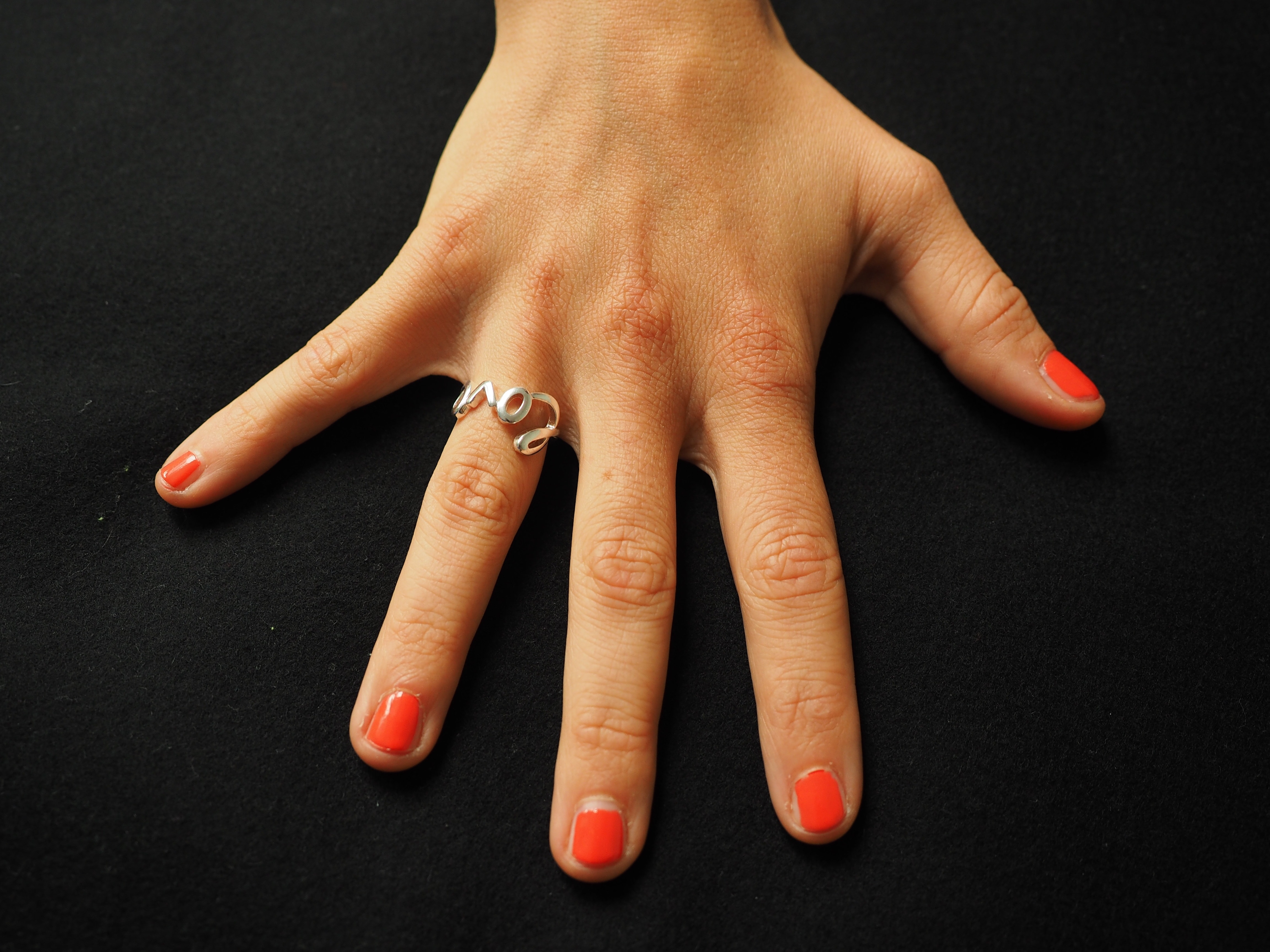 orange nail polish and silver love ring