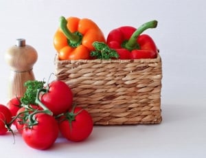 brown wicker basket, six red tomatoes, two orange and red bell peppers thumbnail