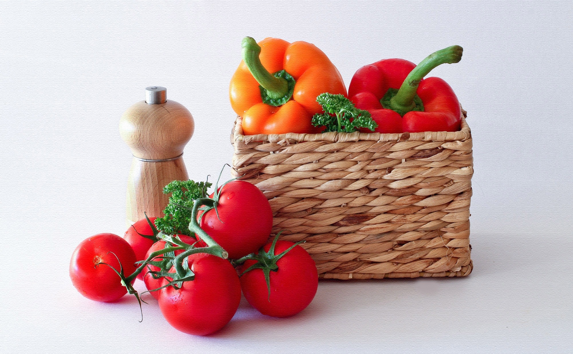 brown wicker basket, six red tomatoes, two orange and red bell peppers