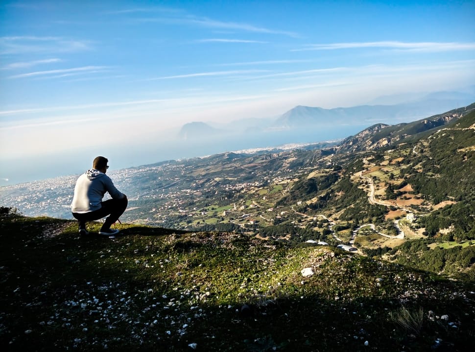 man sitting on the edge of a mountain preview